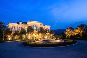 A large, well-lit building with a fountain in the center of a landscaped area. - Chateau de Khaoyai Hotel & Resort (Pak Chong)