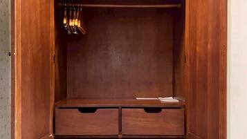 A wooden wardrobe with open doors, revealing a hanging rod and multiple drawers.