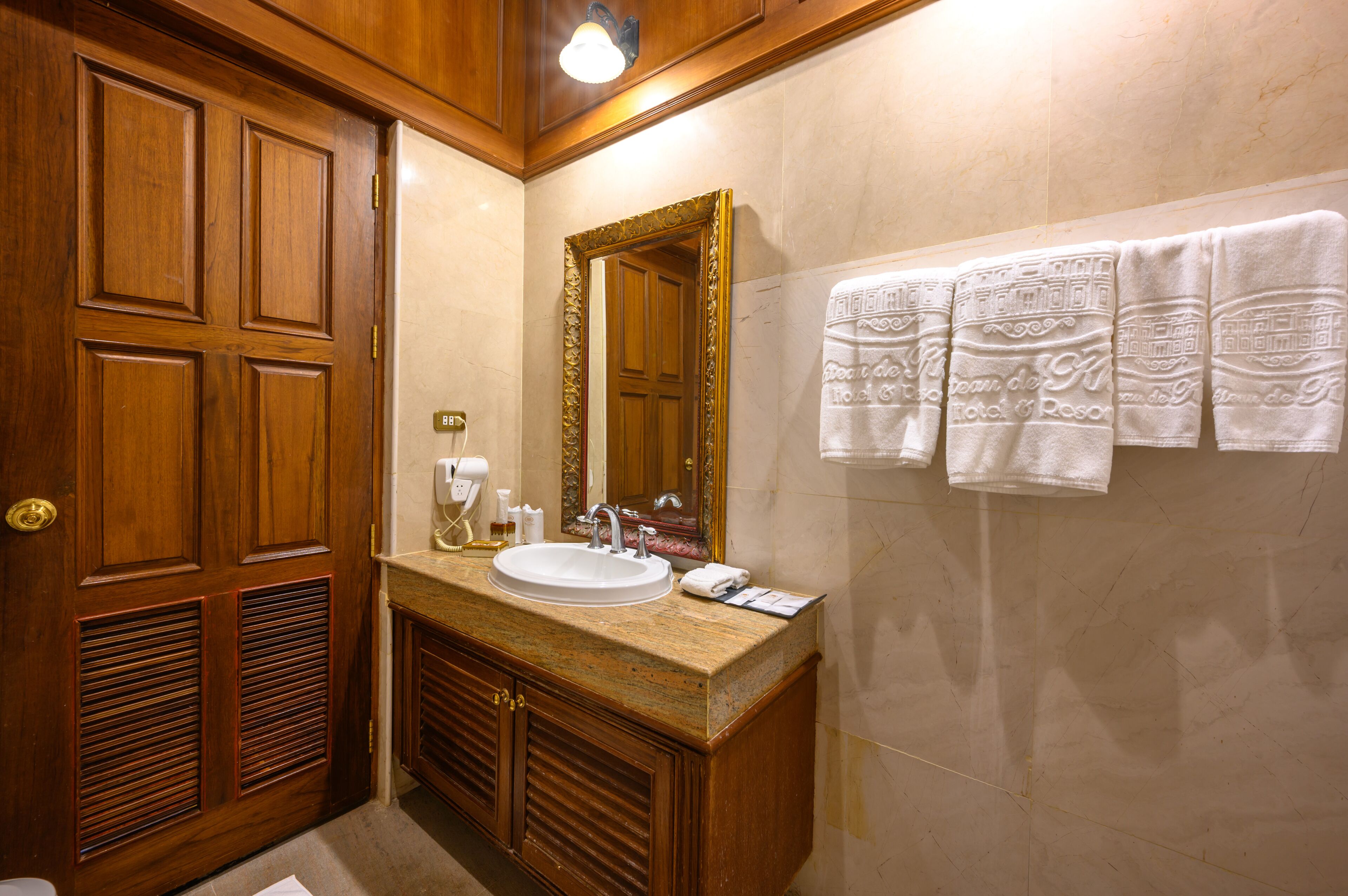 A bathroom with a wooden vanity, a sink, a mirror, and a towel rack with patterned towels.