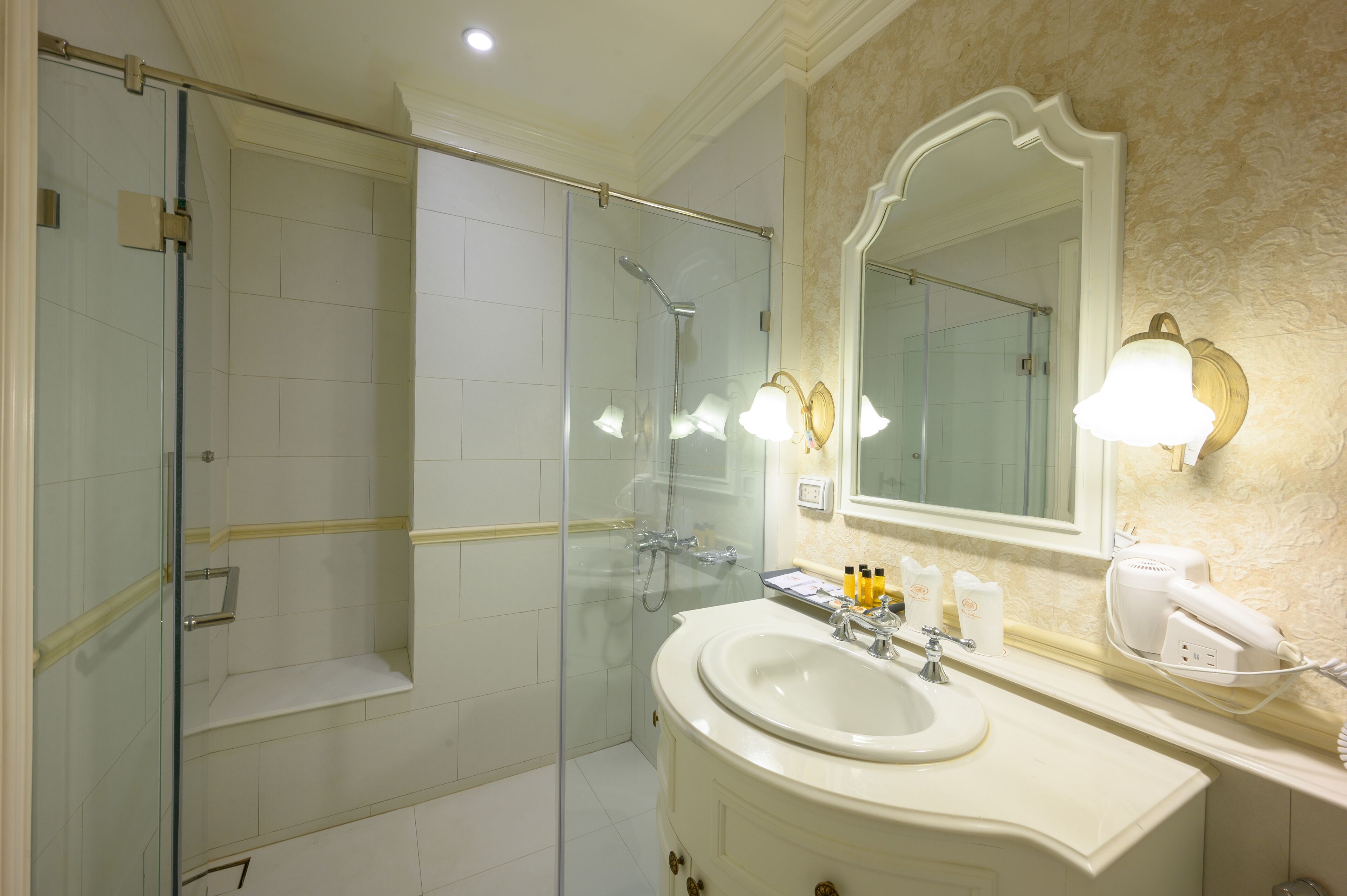 A modern bathroom with a glass-enclosed shower, a large mirror, and a vanity with a sink and toiletries.
