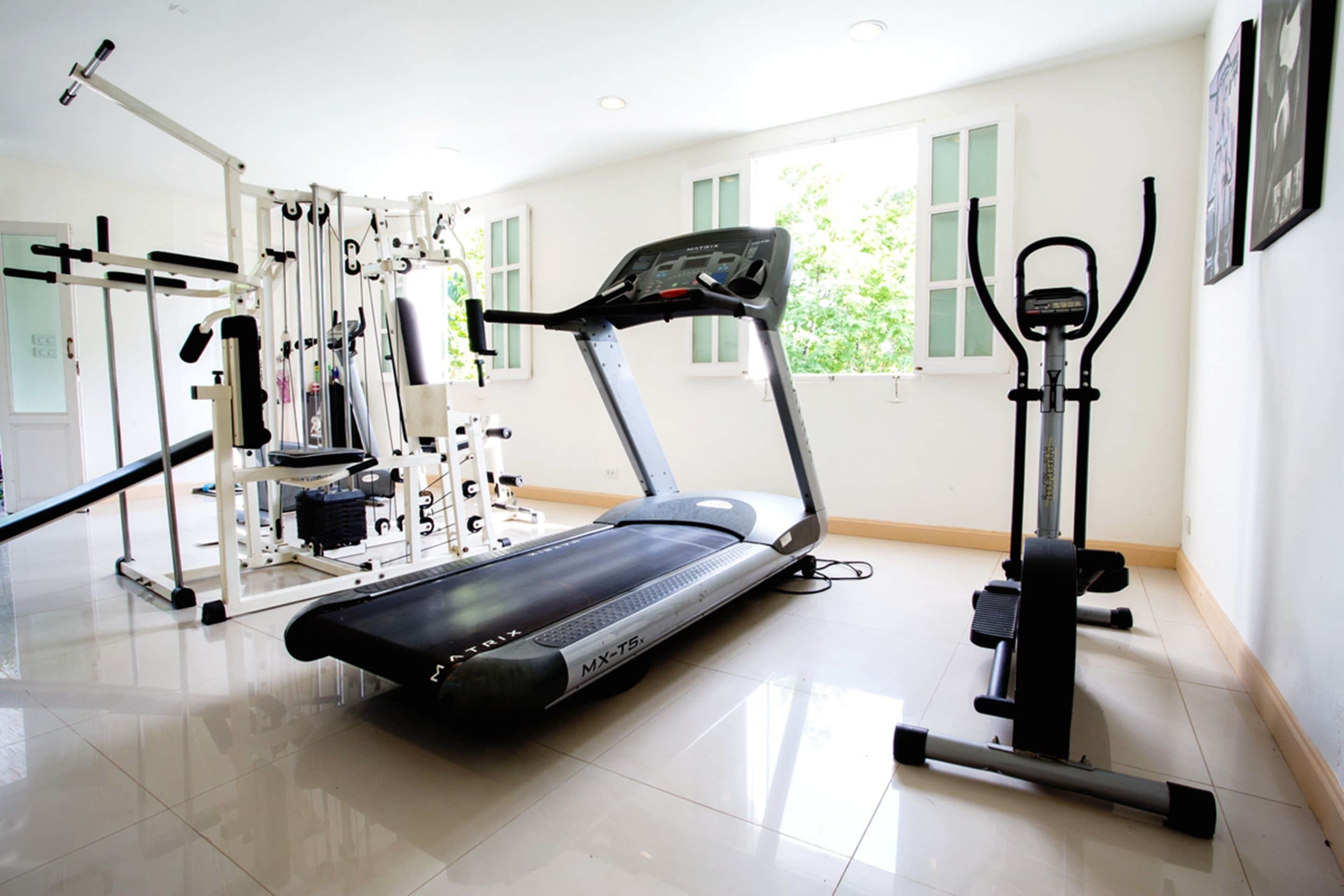 A gym with a treadmill, elliptical, and weight machines.