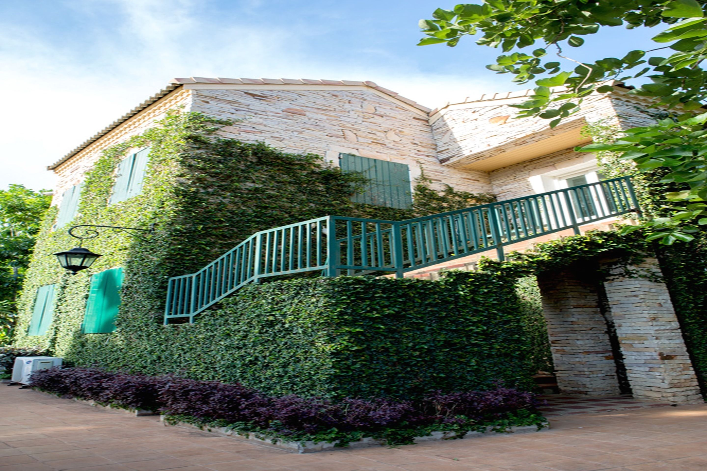 A stone building with a staircase and a green railing.