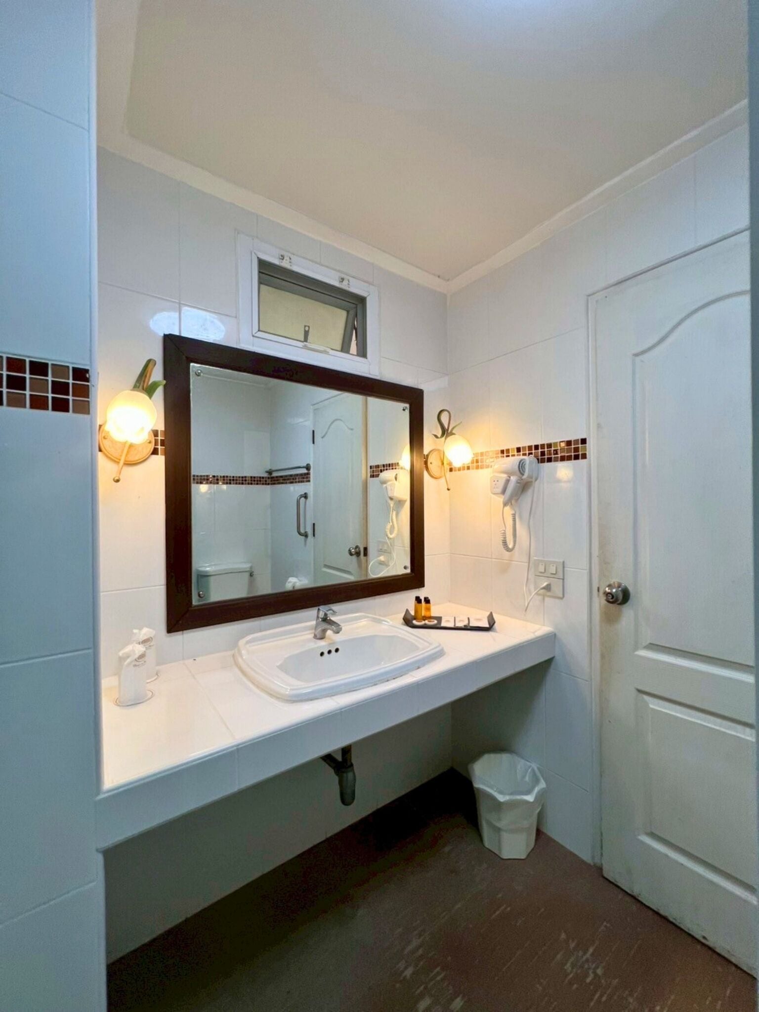 A bathroom with a white sink, a large mirror, and a door.
