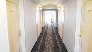 A hotel hallway with carpeted floors, white walls, and doors with numbers. - APA Hotel Owariichinomiya Station (Ichinomiya)