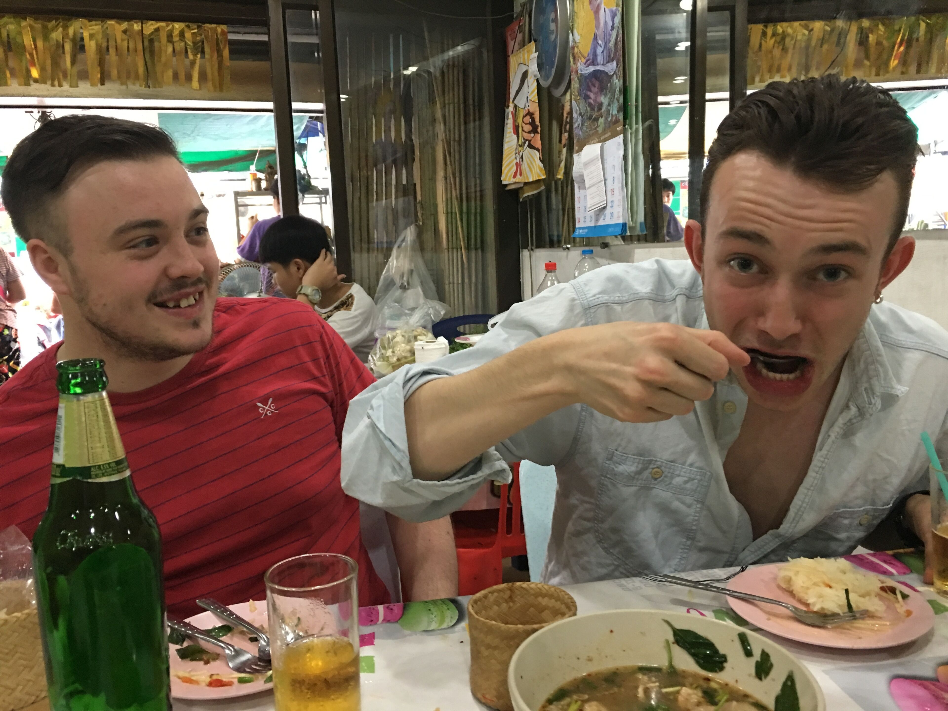 Two people sitting at a table with food and drinks.