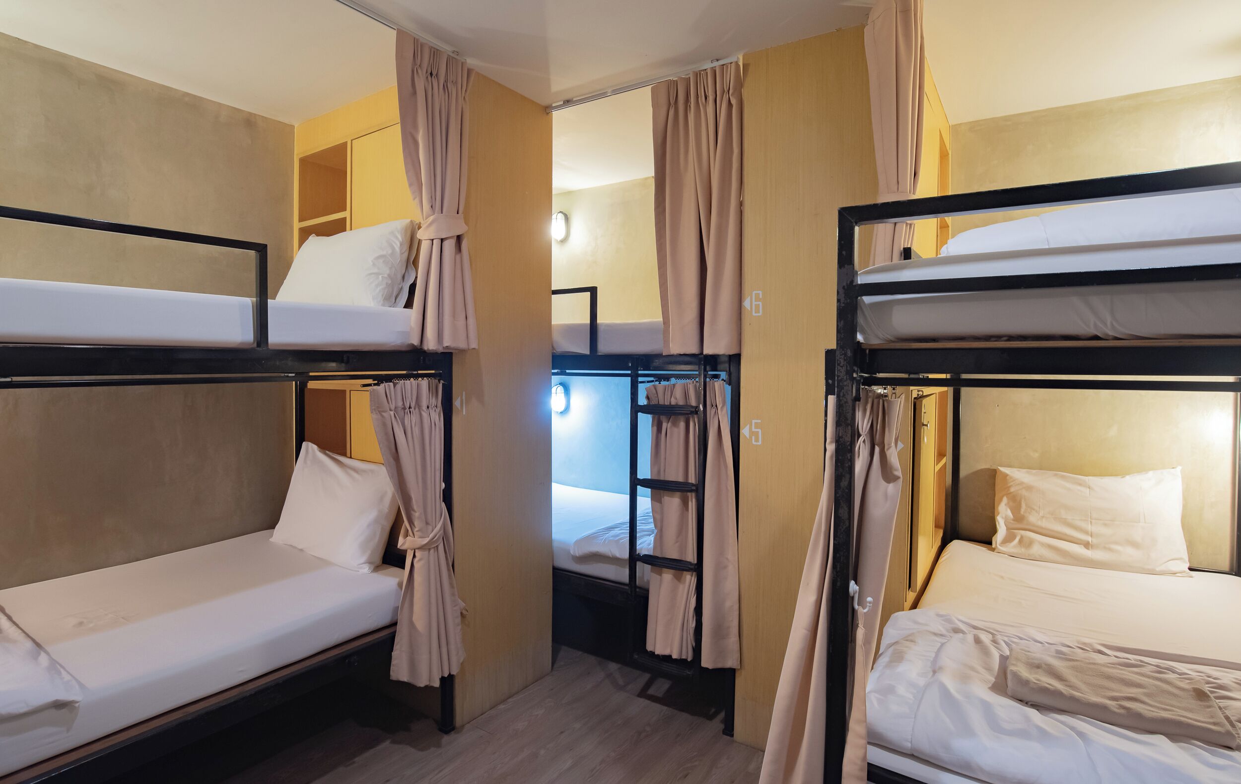 Una habitación tipo dormitorio con literas, cortinas y un armario pequeño.