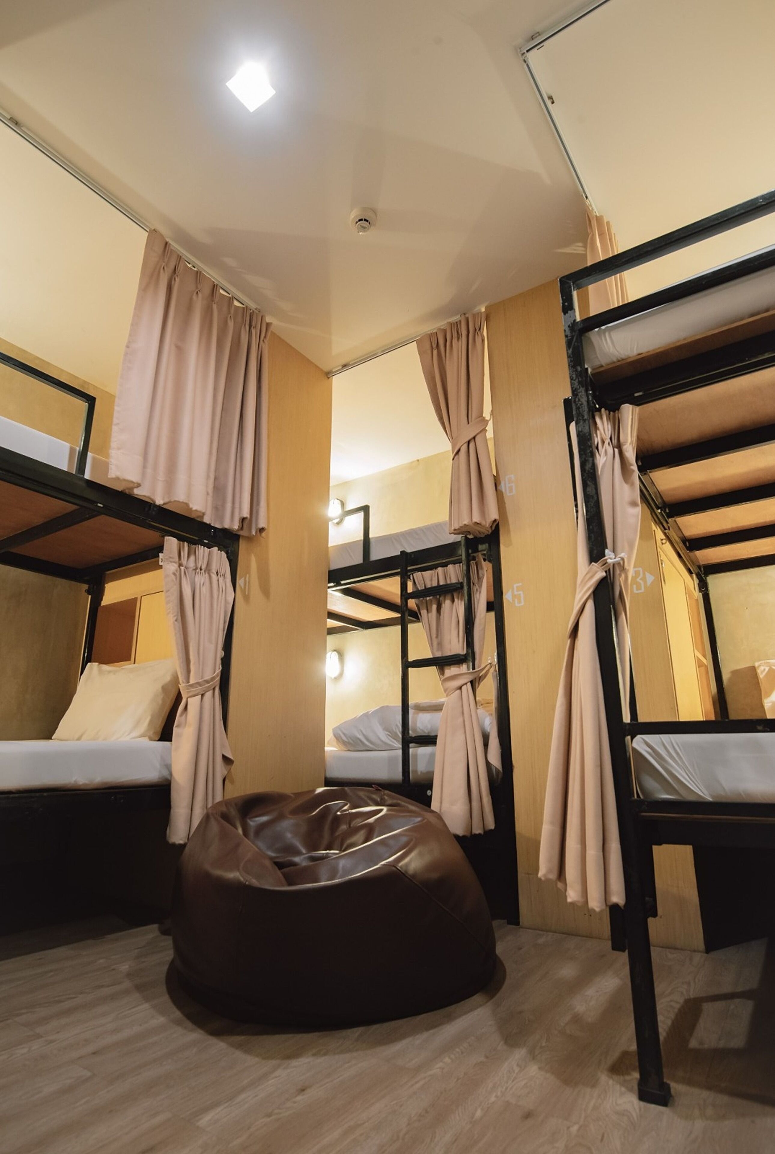 Habitación tipo dormitorio con literas, un sillón de peluche y cortinas.