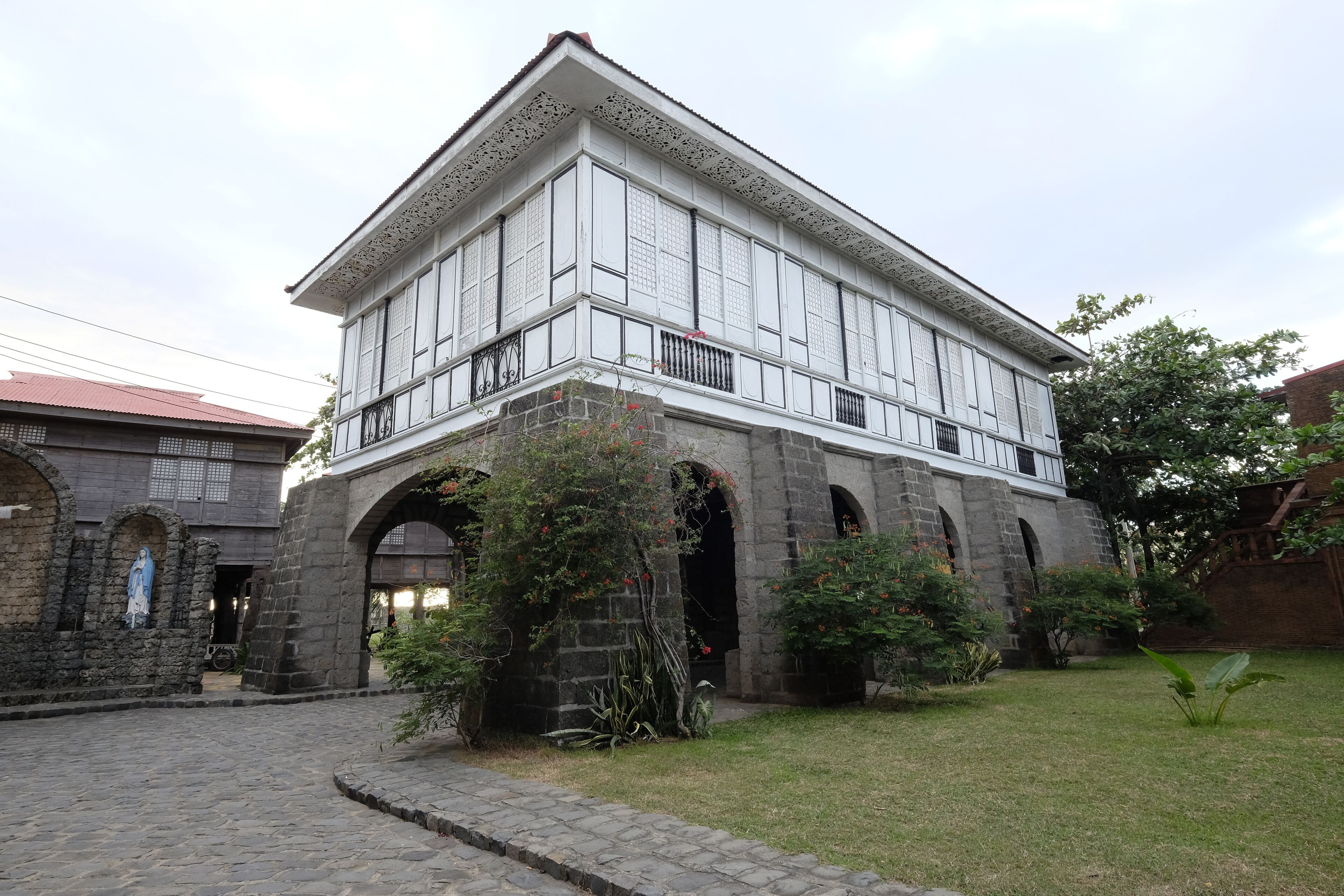 Un edificio tradicional con una estructura de dos pisos, arcos de piedra y un patio.