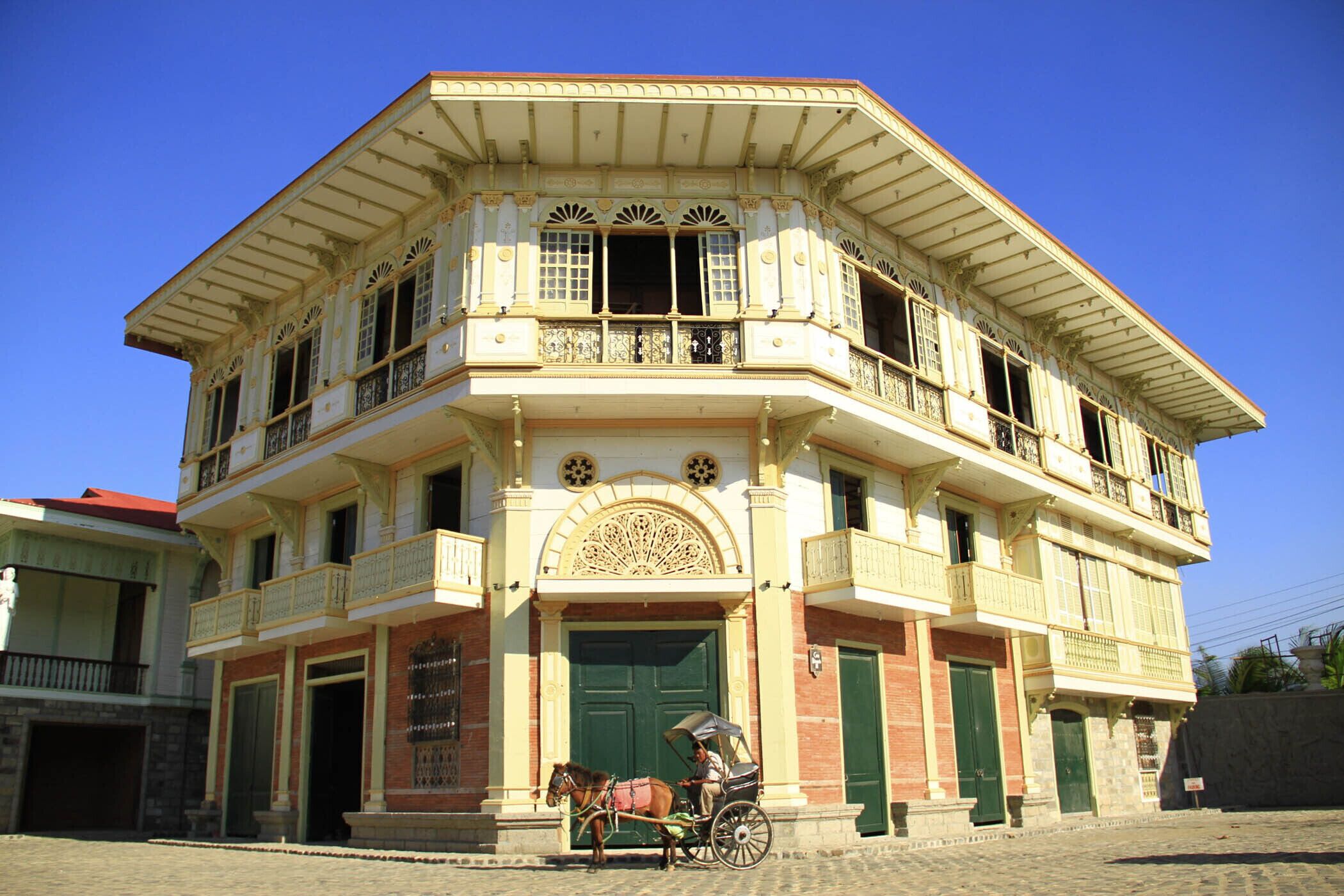 A historic building with a balcony, a horse-drawn carriage, and a green door.