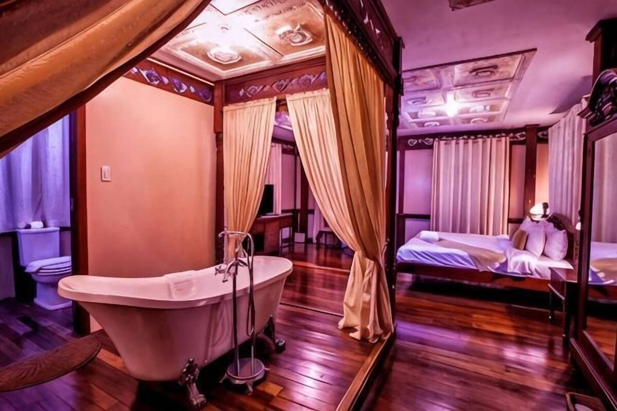 Une pièce avec une grande baignoire, un lit et un miroir.