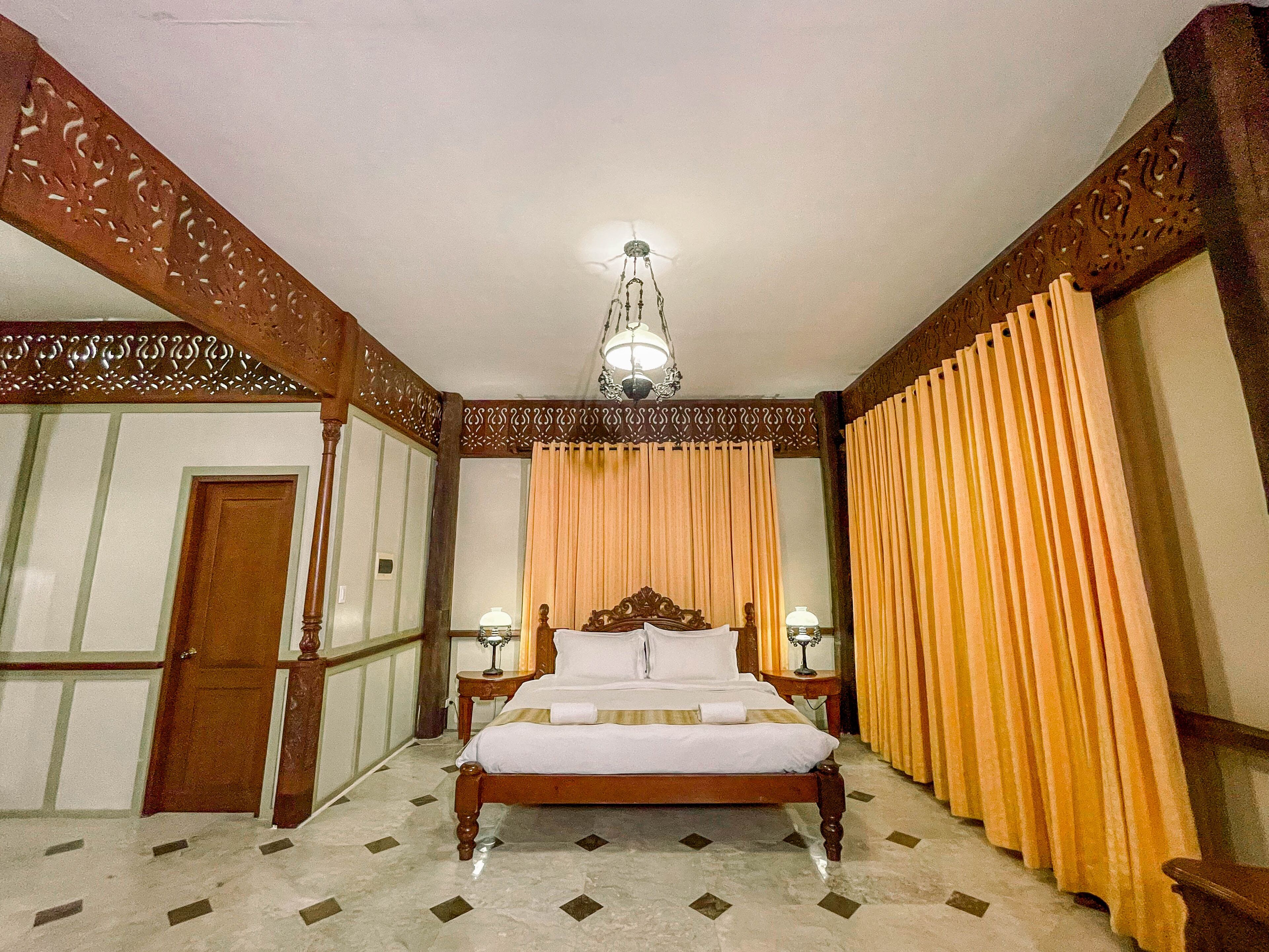A spacious bedroom with a large bed, wooden headboard, and a chandelier.