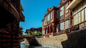 Een historisch gebouw met gedetailleerd baksteenwerk en grote ramen, een stenen brug en een gracht.