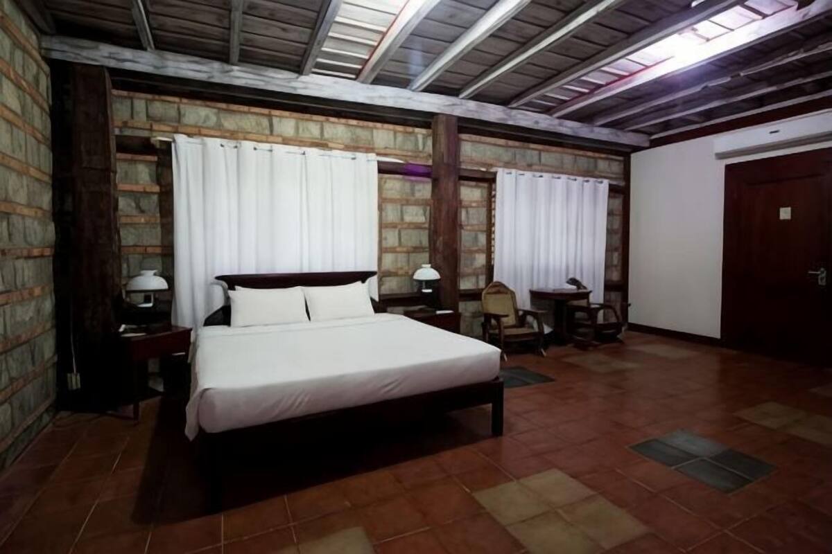 Une chambre à coucher avec un lit, deux tables de chevet, une chaise, une porte et une fenêtre.