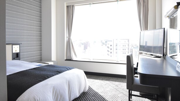 A hotel room with a large window, a bed, a desk with a chair, and a television. - APA Hotel Mito-ekimae (Mito)