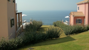 A coastal view with a building, a grassy area, and a clear sky.
