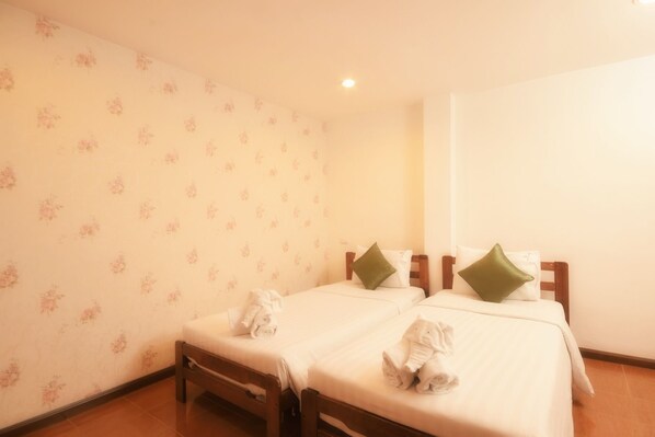 Habitación de hotel con dos camas, papel tapiz floral y cabecera de madera.