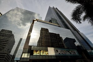 Un moderno edificio de gran altura con fachadas de vidrio reflectante y un anuncio destacado de una clínica quiropráctica.