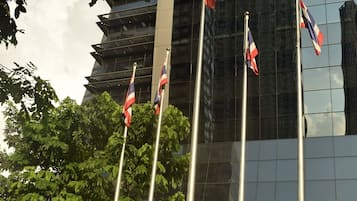 The exterior of the Stock Exchange of Thailand with flags, a water feature, and a modern glass building in the background.