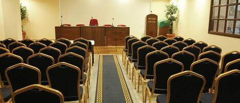 A conference room with rows of chairs, a podium, and a carpet with a geometric pattern.