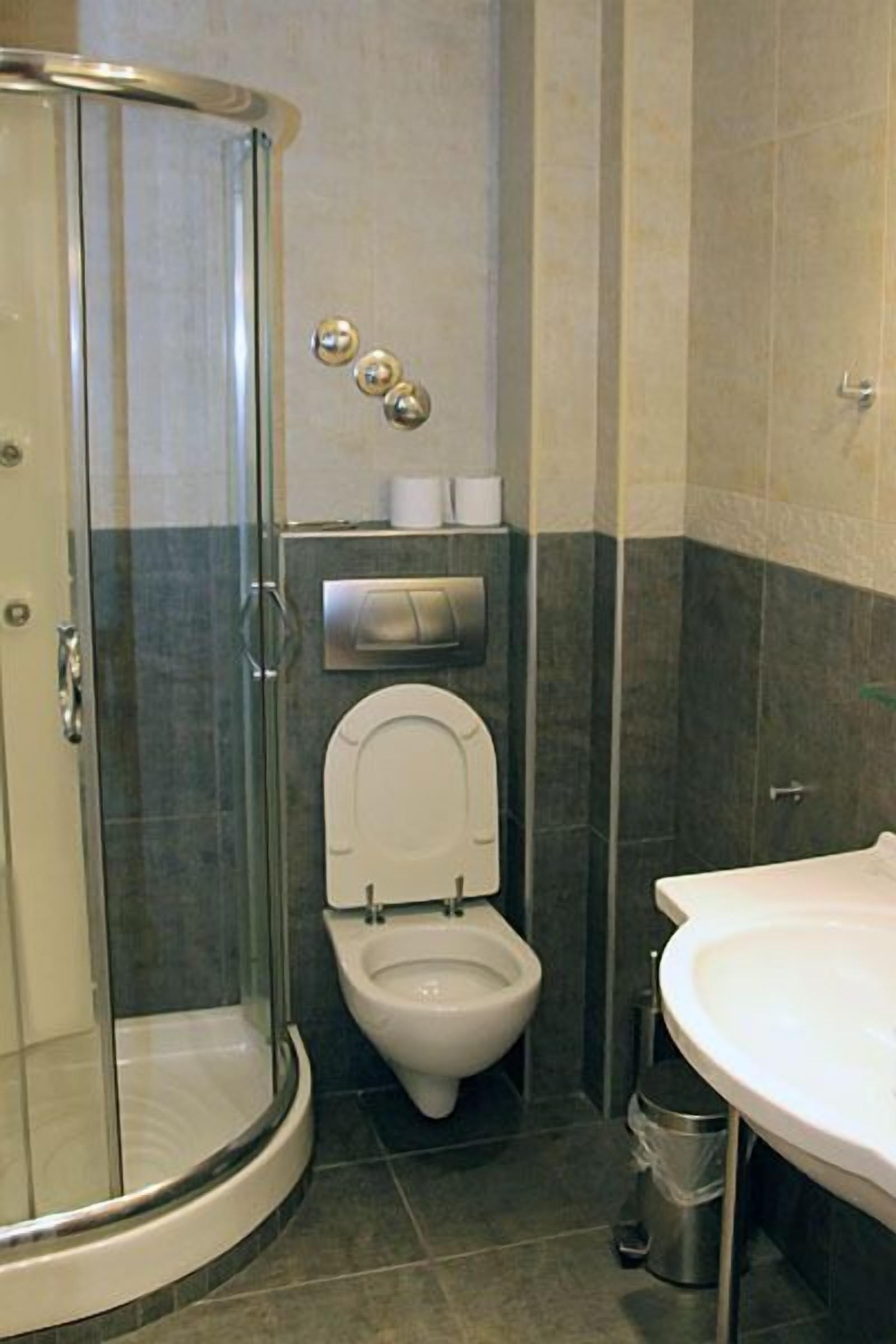 Casa de banho com cabine de duche em vidro, sanita e lavatório.