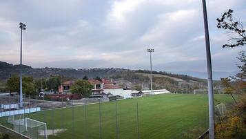 A soccer field with goalposts, floodlights, and a building in the background.