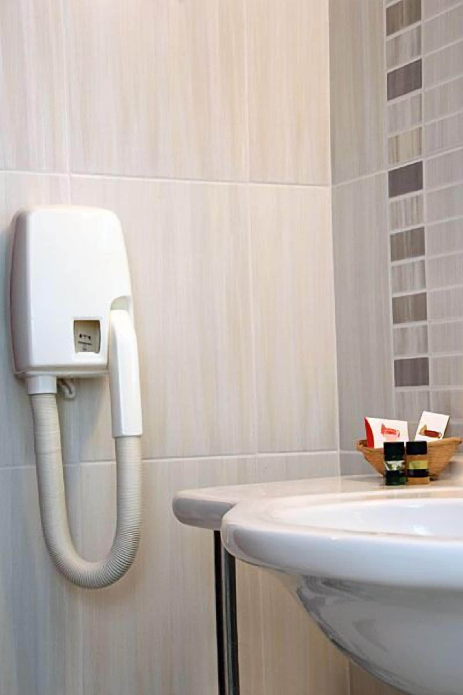 A bathroom with a white sink, a white telephone, and a small wooden tray with toiletries.