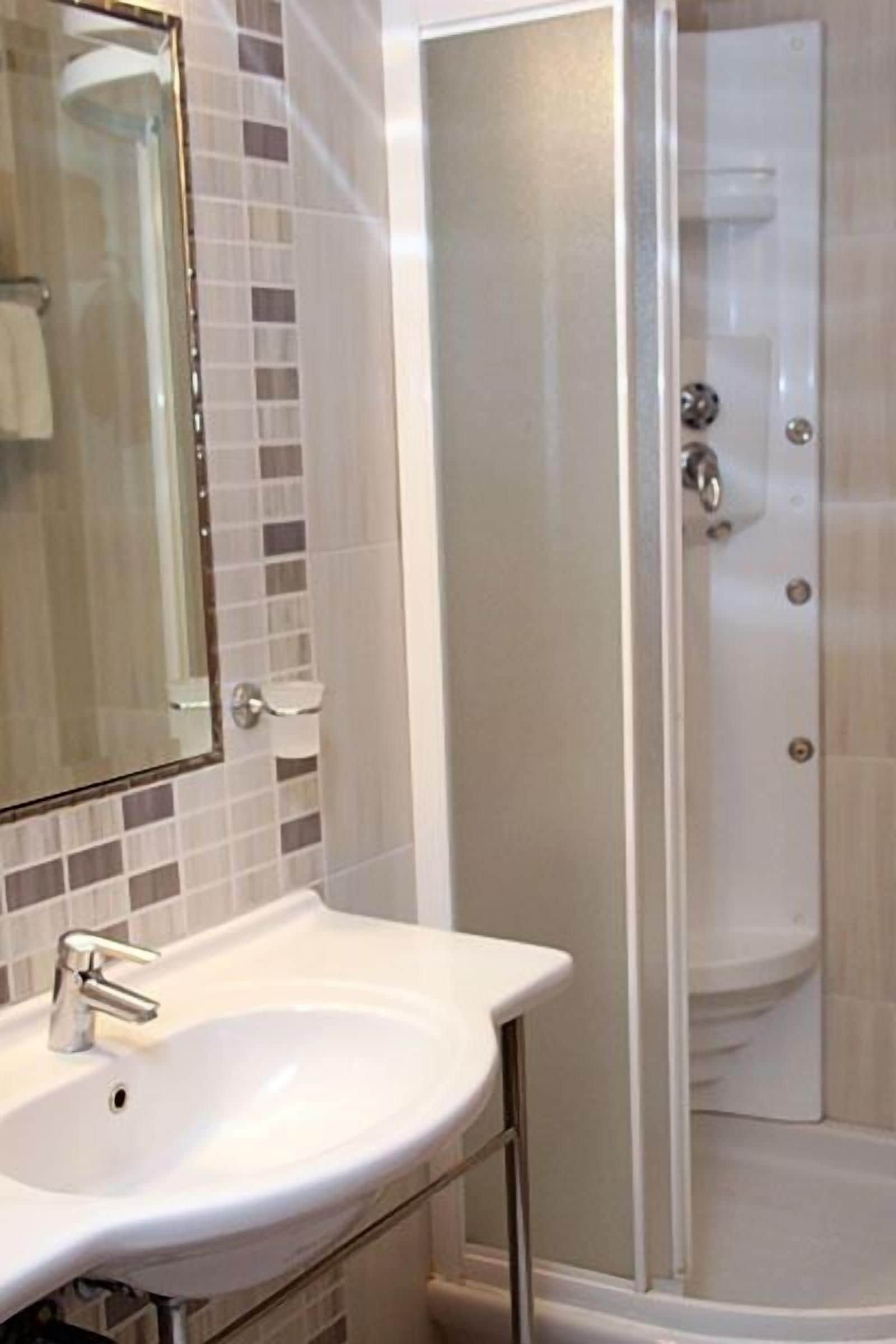 A bathroom with a white sink, a mirror, and a glass-enclosed shower.