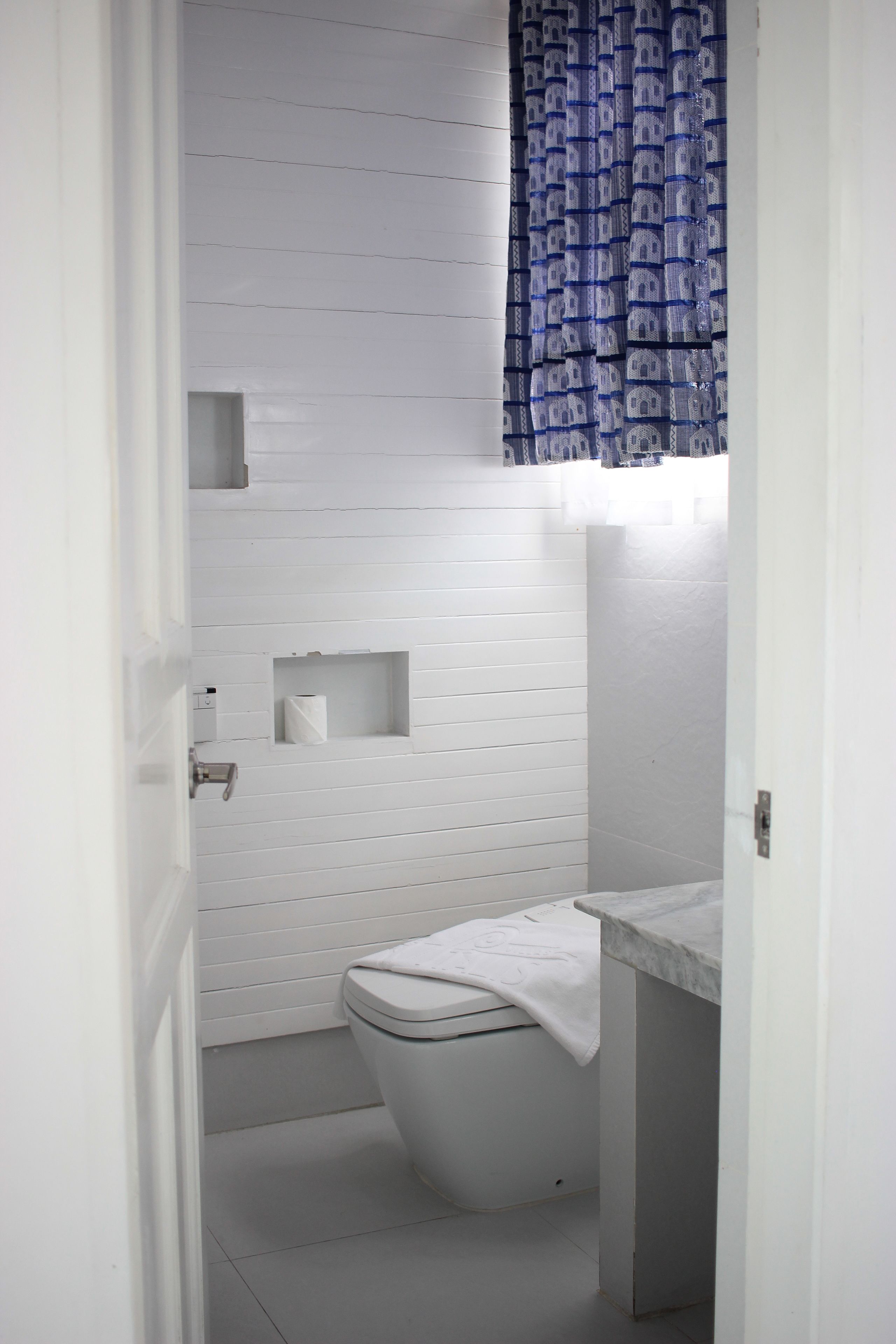 A small, white bathroom with a toilet, a sink, and a shower area.