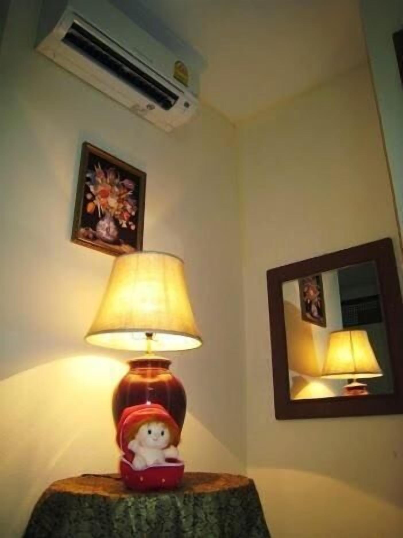 Une lampe avec un pied rouge et un abat-jour blanc, posée sur un tabouret en bois.