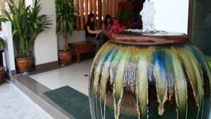 A large, colorful fountain in a lobby area with potted plants and a seating area in the background.