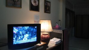 A television on a stand, a lamp, and a sign on the wall.