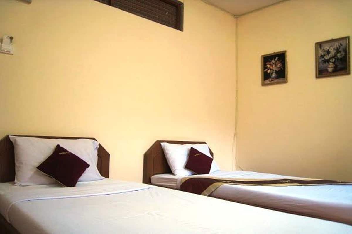 Quarto de hotel com duas camas de solteiro, cada uma com travesseiro e cobertor.