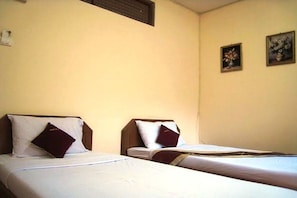 Ein Hotelzimmer mit zwei Einzelbetten, jeweils mit Kissen und Decke.