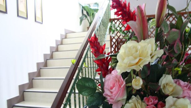 A staircase with a handrail and a floral arrangement at the top.