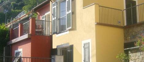 A two-story building with balconies and a stone wall.