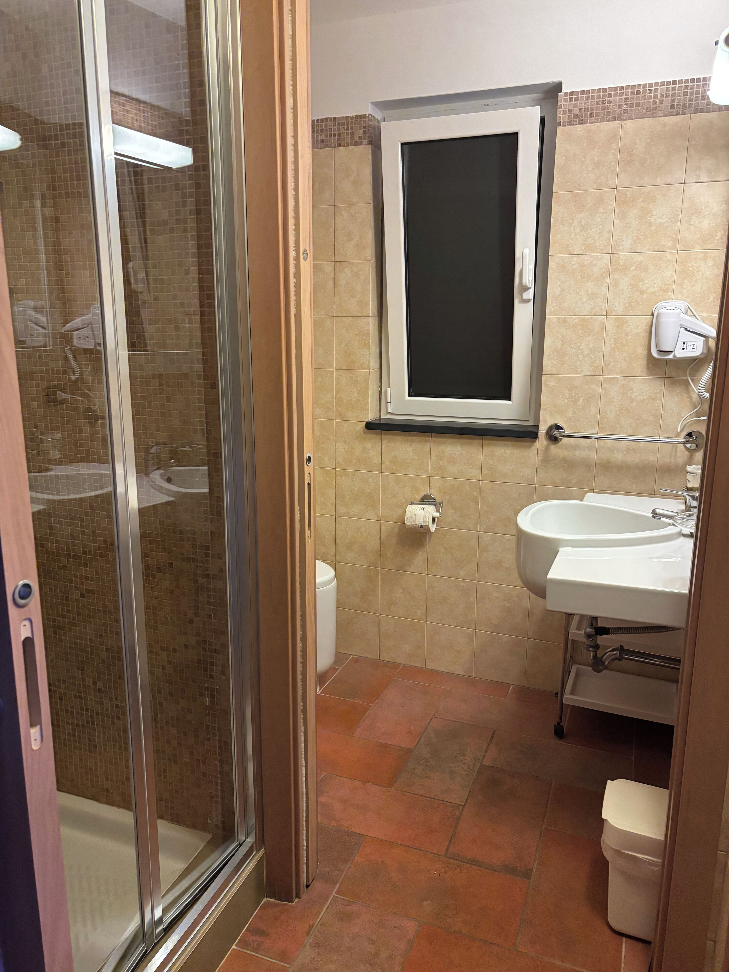 Un baño con mampara de vidrio, lavabo e inodoro.