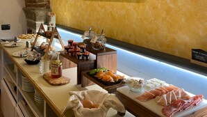 A buffet setup with various food items, a framed painting on the wall, and a stone archway. - Locanda Ca Da Iride (Riomaggiore)
