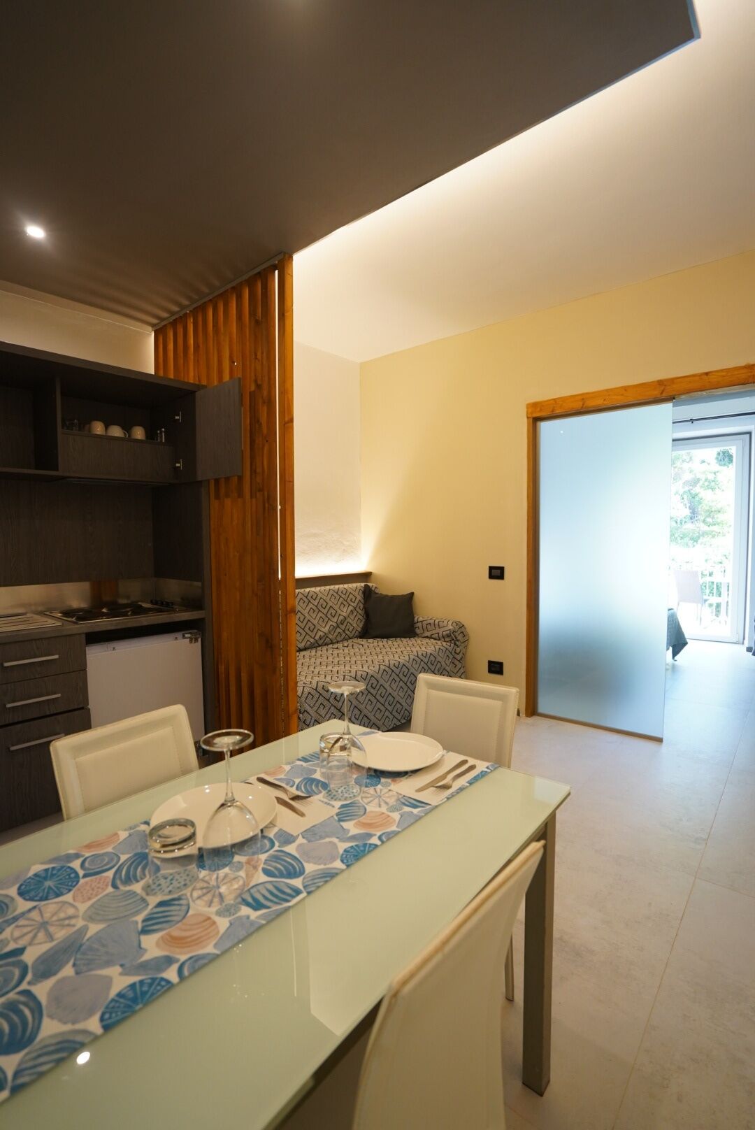 A modern kitchen with a dining area, a built-in oven, and a small refrigerator.