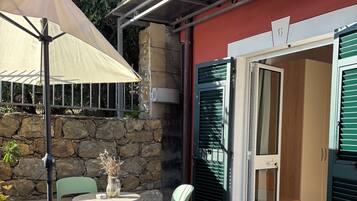 A patio area with a table and chairs, a stone wall, and a door leading to a room.