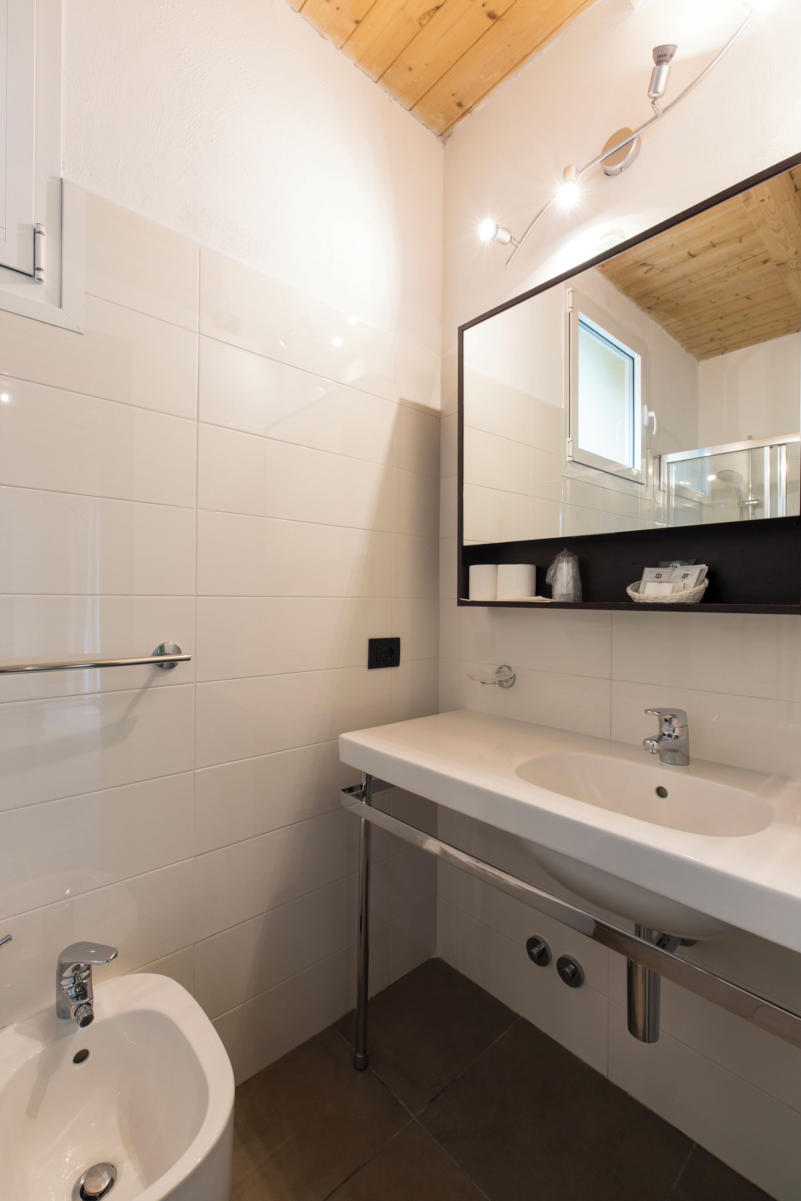 Un bagno moderno con un lavandino bianco, uno specchio e una doccia.
