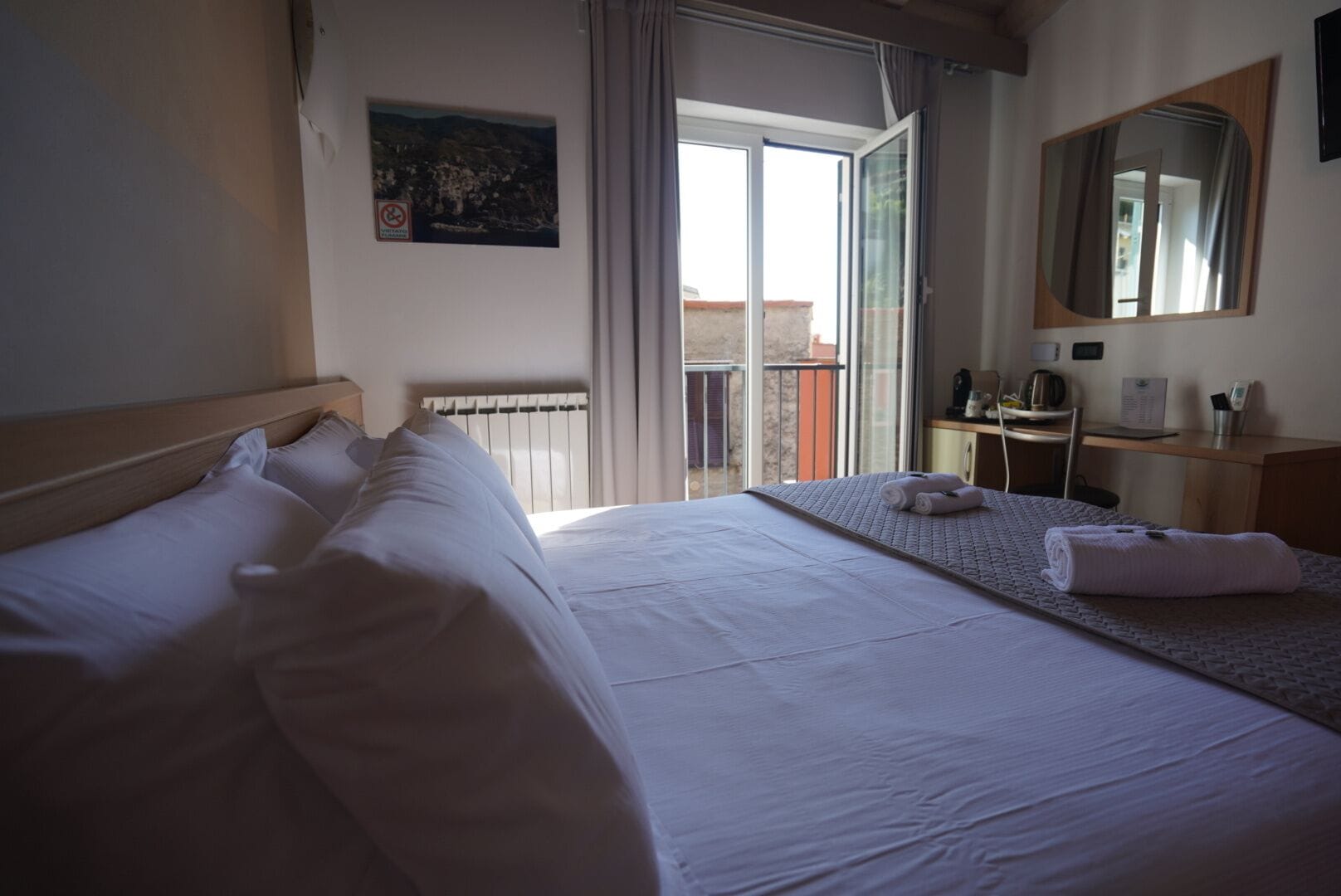 Una camera d'hotel con un letto grande, una scrivania, una sedia, uno specchio e vista sull'esterno.