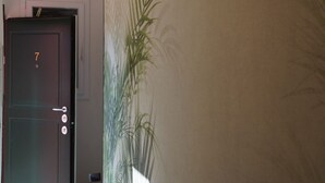 A hallway with a door marked '7', a wall-mounted plant, and a light fixture. - Locanda Ca Da Iride (Riomaggiore)