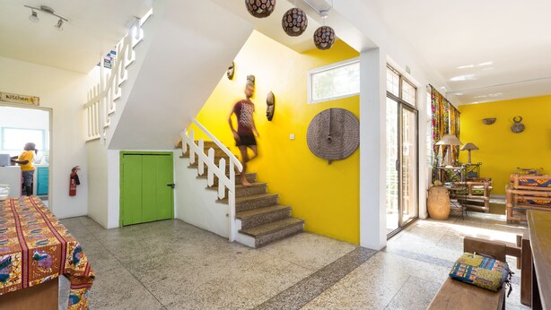 A bright interior with a staircase, a kitchen area, and a dining space. - Agoo Hostel (Accra)