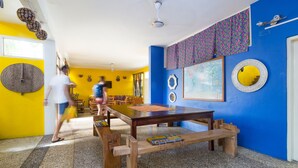A room with a wooden table, benches, and a blue wall with decorative items. - Agoo Hostel (Accra)
