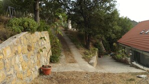 A stone wall with a pathway leading to a house with a red-tiled roof. - B&B L'Intrigante (Seborga)