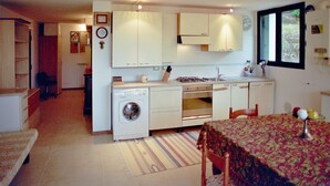 A compact kitchen with white cabinets, a washing machine, and a dining area with a table and chairs. - B&B L'Intrigante (Seborga)