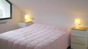 A bedroom with a large bed, two bedside tables with lamps, a window, and a radiator. - B&B L'Intrigante (Seborga)