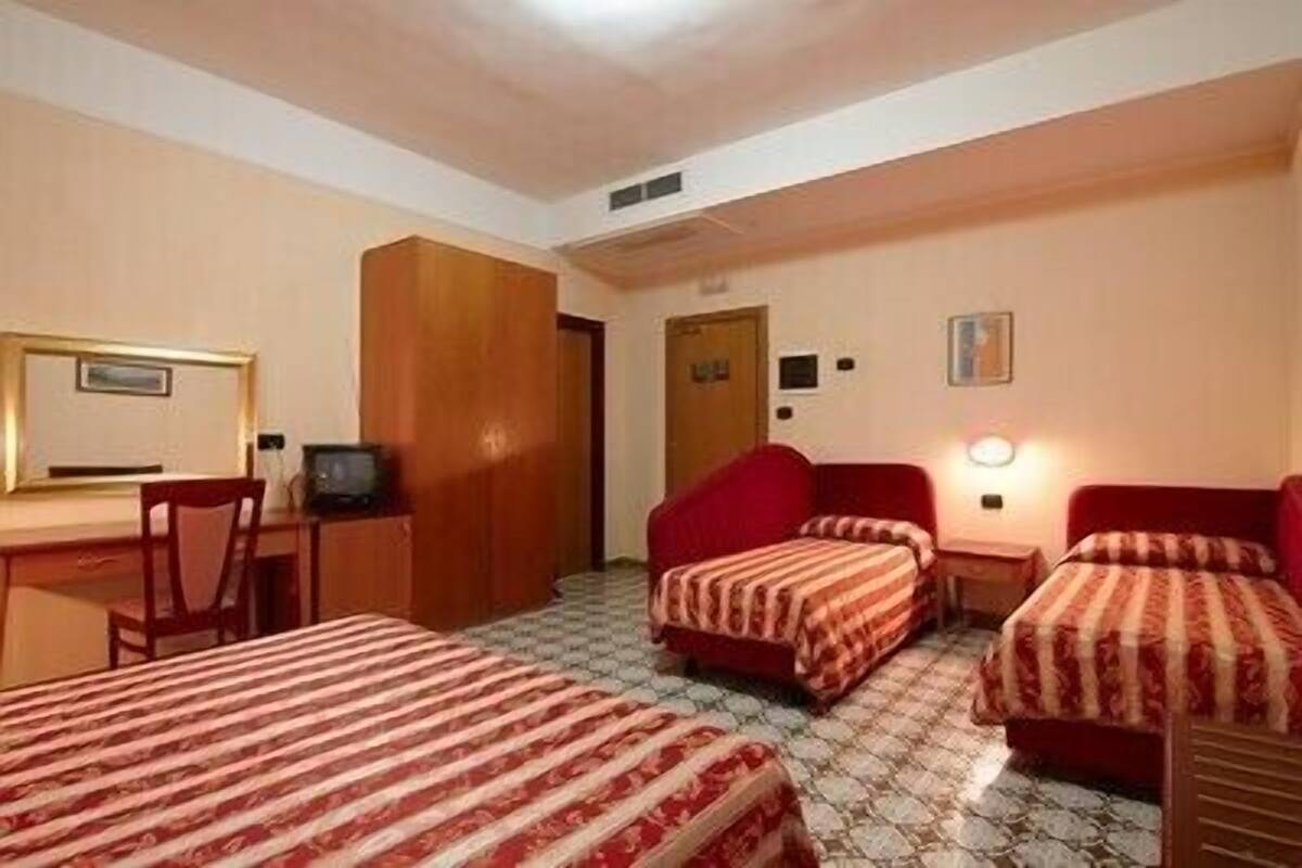 Una habitación de hotel con dos camas, un escritorio, una silla, un televisor y una puerta.