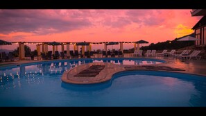 Una piscina al aire libre, sombrillas, sillones reclinables de piscina