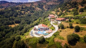 An aerial view of a resort with a swimming pool, multiple buildings, and a winding road. - Loggas Hotel (Kastoria)